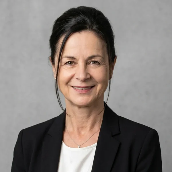 Professional woman in a black blazer smiling at the camera against a gray backdrop.